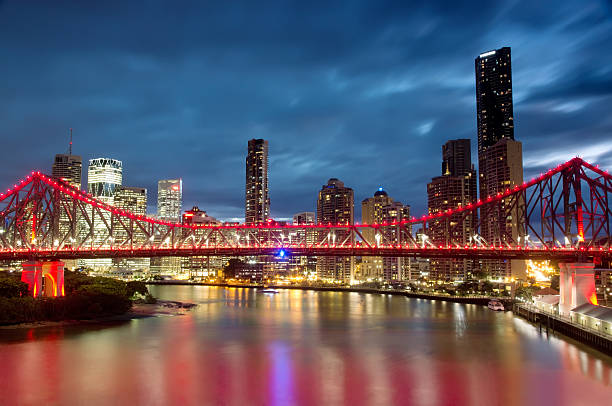 Brisbane Skyline - Dusk The Story Bridge is illuminated in red at dusk, before skyscrapers in the Brisbane CBD. story bridge photos stock pictures, royalty-free photos & images