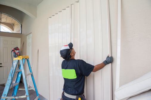 Contractor installing hurricane shutters.  rr