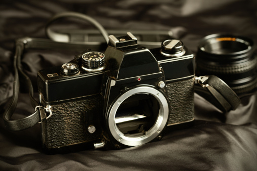 Dirty vintage camera with lens in the background.