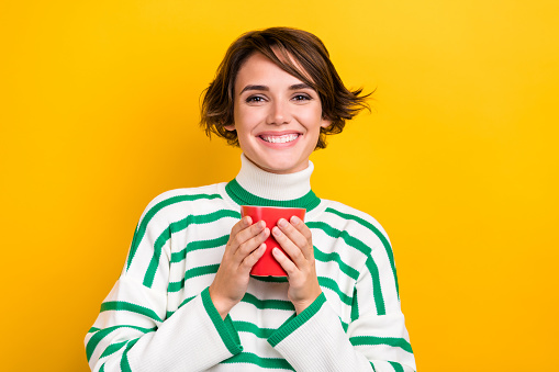 Photo of cute adorable lady wear striped pullover enjoying hot tasty beverage isolated yellow color background.