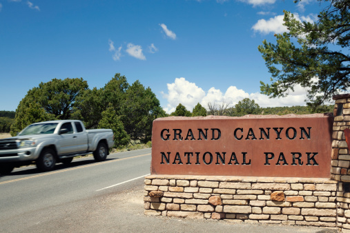 Car passing by the entrance sign at the Grand Canyon National Park.