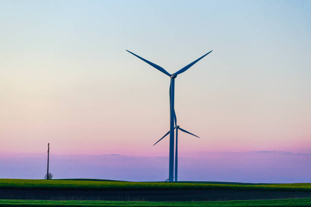 Horizontal axis wind turbines on agricultural field after beautiful sunset, blue and purple horizon, sustainable energy and future resources