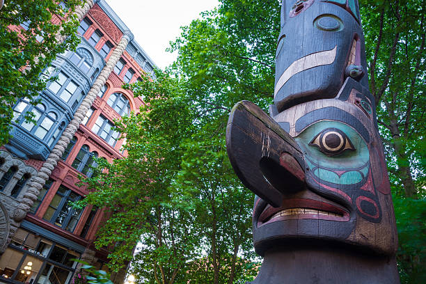 Totem pole at Pioneer Square in Seattle, WA Totem pole at Pioneer Square in Seattle, WA with the Pioneer Building in the background, which was originally constructed in 1892. totem pole face stock pictures, royalty-free photos & images