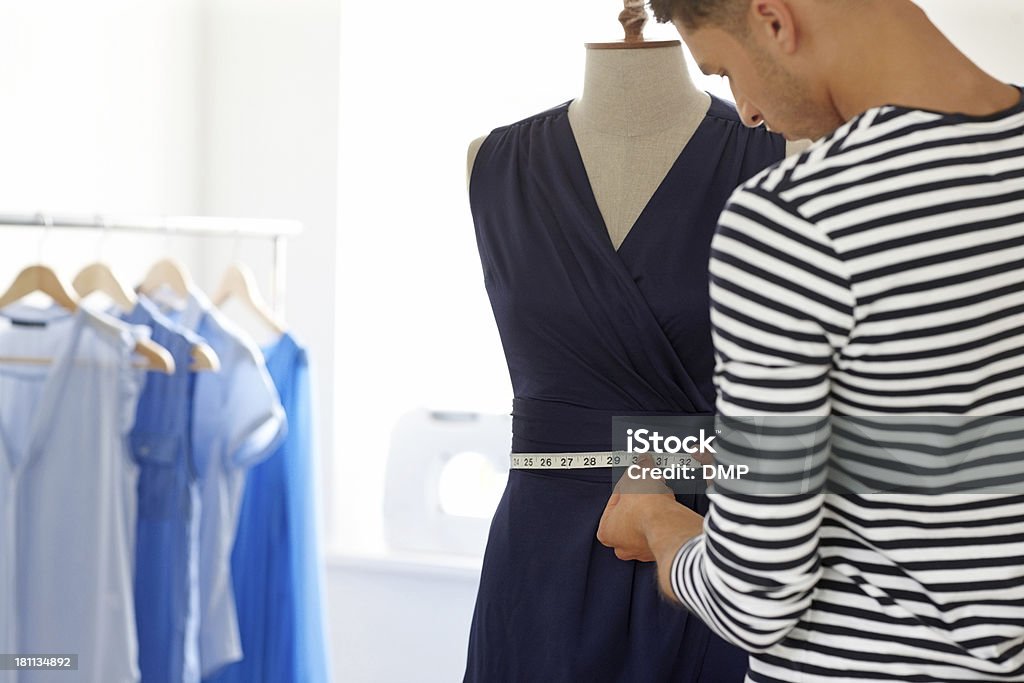 Young male designer taking measures on a mannequin Young male designer taking measures on a mannequin with tape measure in fashion studio 20-29 Years Stock Photo