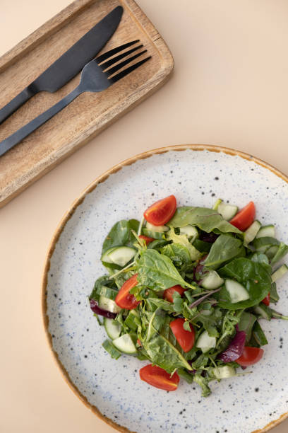 istock Fresh salad with arugula, cherry tomatoes, cucumbers in a plate on a color background. 1811351441