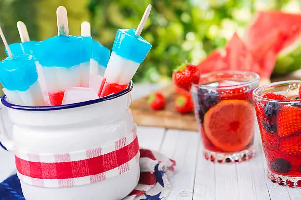 Homemade red-white-and-blue popsicles on an outdoor table.