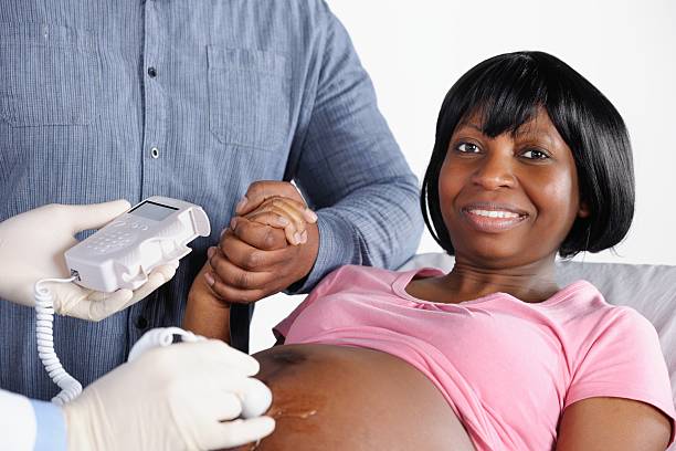 afro-americana mulher feliz tendo um fetais doppler/avaliação de pré-natal - midwife human pregnancy women multi ethnic group - fotografias e filmes do acervo
