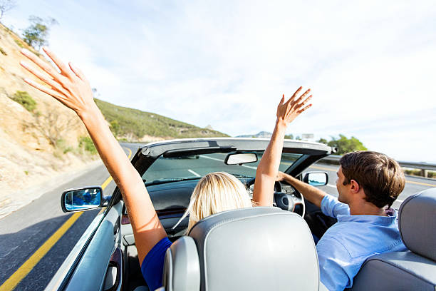 istock Woman Enjoying Road Trip While Man Driving Convertible Car 181135785