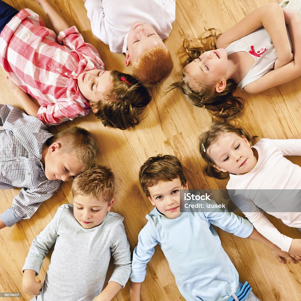 Nursery School Children High angle view of cute nursery school children lying in circle on the floor. Child Stock Photo