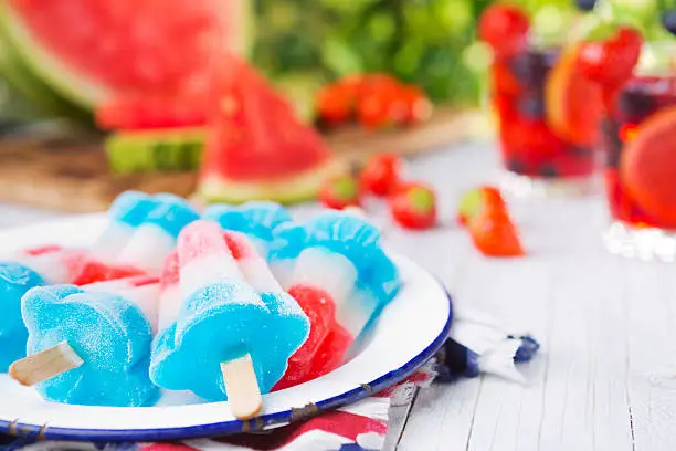 Homemade red-white-and-blue popsicles on an outdoor table.