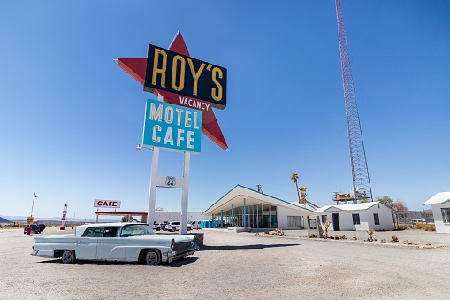 Amboy, United States – August 03, 2023: A retro car parked near the sign of Roy's Motel cafe