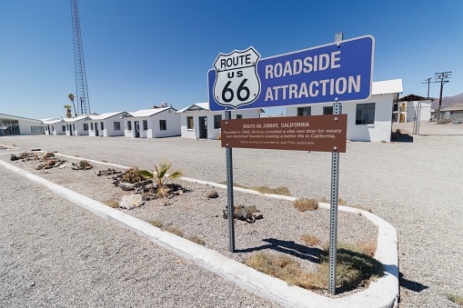 Amboy, United States – August 03, 2023: The Route 66 sign with a row of white buildings in the background. Amboy, California