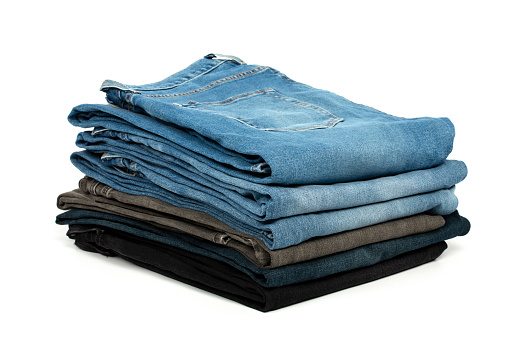 Stack of various denim jeans, trousers isolated on white