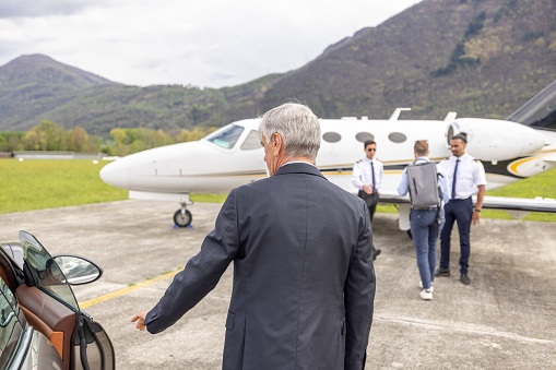 Young corporate businessman walking on tarmac toward private jet plane
The pilot greets him, welcome aboard