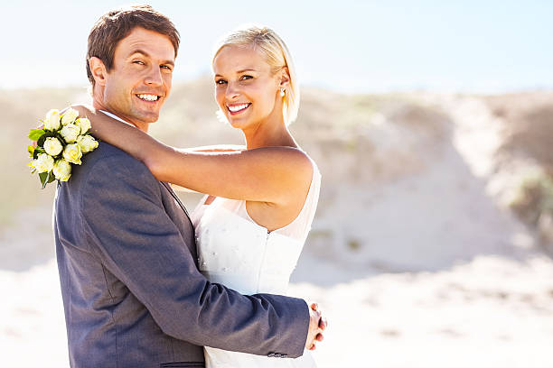 istock Newlywed Couple Embracing On The Beach 181138387