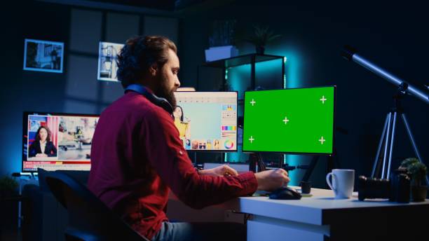 istock Photographer uses photo editing software on green screen PC display in personal studio 1811386792