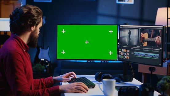 Videographer uses editing software on green screen computer to assemble footage into cohesive final result. Expert color correcting clips on mockup monitor to ensure project meets desired aesthetic