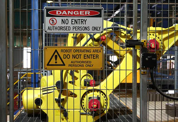 No entry for persons warning signs outside a robotic assembly line with robot in background