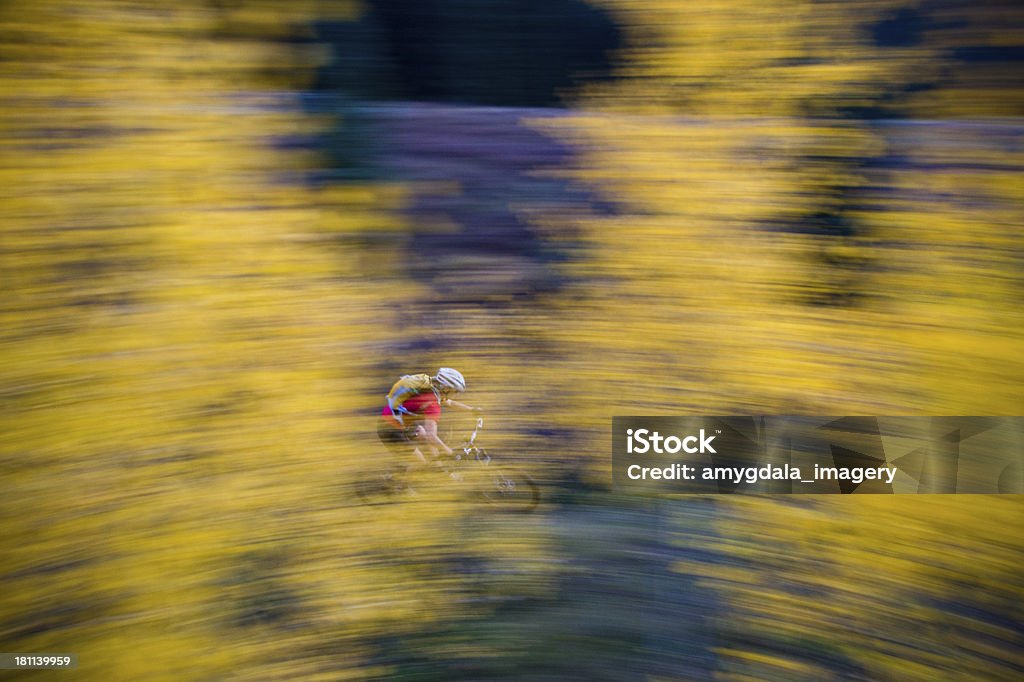 abstract mountain biking motion mountain bike rider rides through golden yellow autumn aspens underneath a cloud filled dramatic sky at sunset.  such beautiful nature scenery and outdoor sports and adventure can be found at the hermosa creek trail in the san juan range of the colorado rocky mountains in durango.  vertical composition with motion blur. Abstract Stock Photo