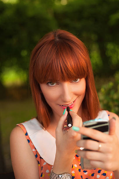 istock Young woman applying lipstick 181140782