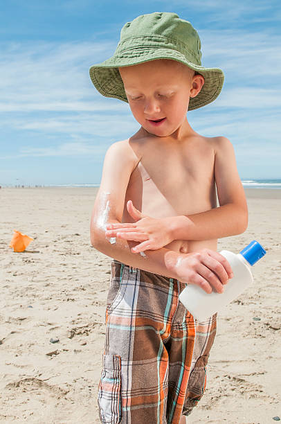 istock Little boy on the beach applying sunscreen. 181140940