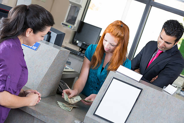 istock Female teller counting money under supervision 181141372