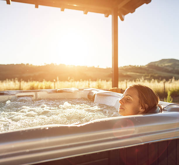 Woman in whirlpool hot tub Woman in whirlpool hot tub at sunset hot tub stock pictures, royalty-free photos & images