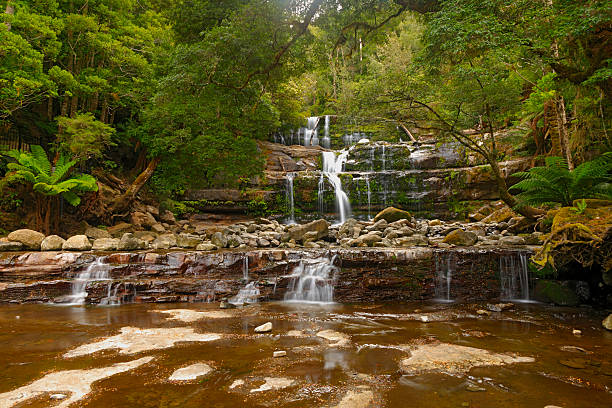 istock Summer rain cascades over rocky waterfall in rainforest 181143011
