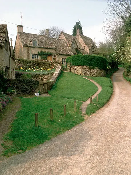 England, Cotswolds, Gloucestershire, Bibury, cotswold cottage and winding country lane