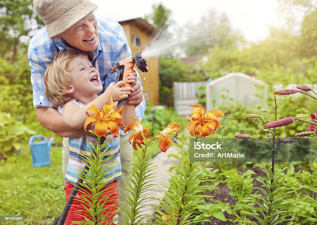 Grandmother and grandson in the garden Happy family watering flowers Gardening Stock Photo