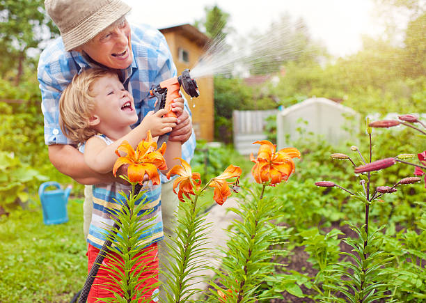 Grandmother and grandson in the garden Happy family watering flowers elder plant stock pictures, royalty-free photos & images