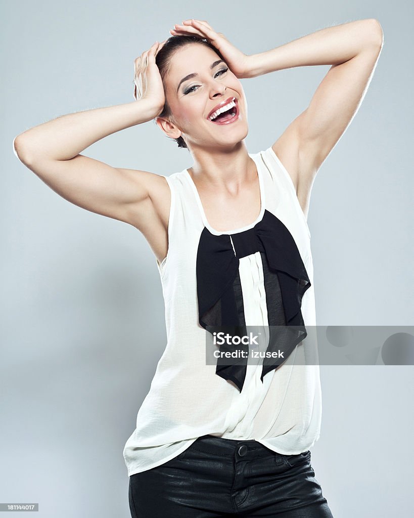 Happiness Portrait of happy young woman raising her arms and laughing at the camera. Studio shot on a grey background. 20-24 Years Stock Photo