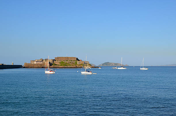 Castle Cornet and Herm Castle Cornet is a large island castle in Guernsey. It is part of the breakwaters of St Peter Port's harbour. People/logos too small to be recognisable. Herm Islandin the background. groyne stock pictures, royalty-free photos & images