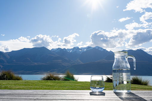 Natural drinking water in a bottle and glass beaker on nature background river.
