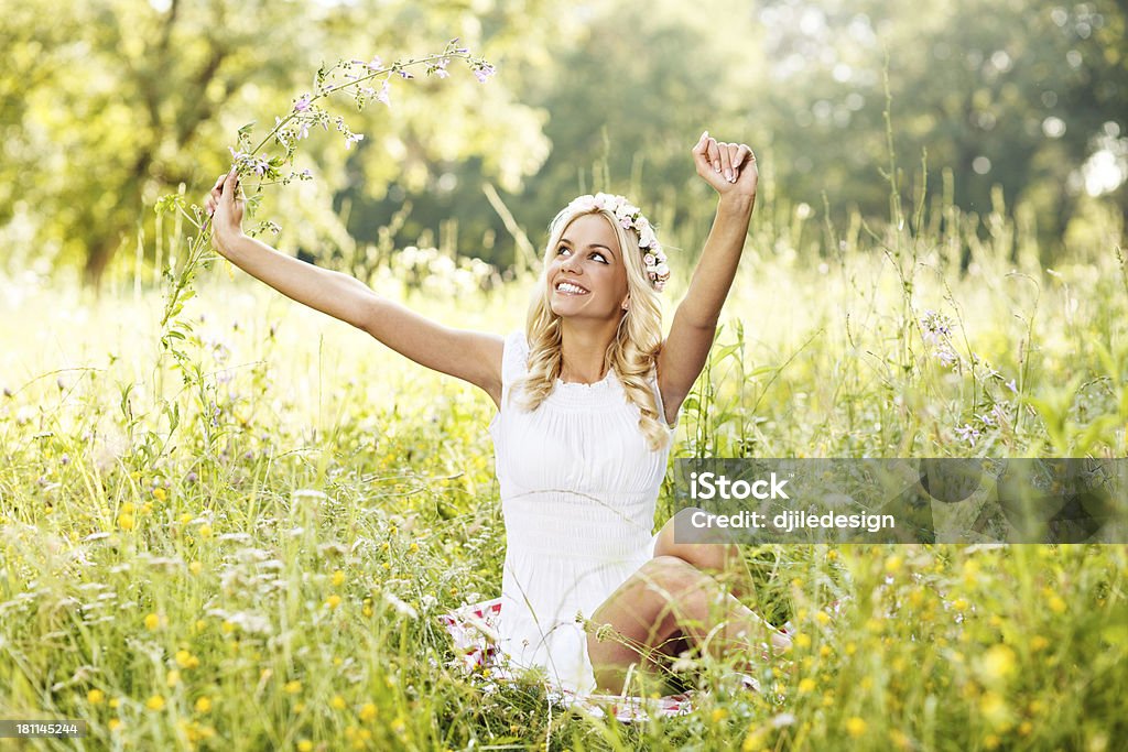 Blonde lying in the field Attractive blonde lying in the field and holding flower in hand Adult Stock Photo