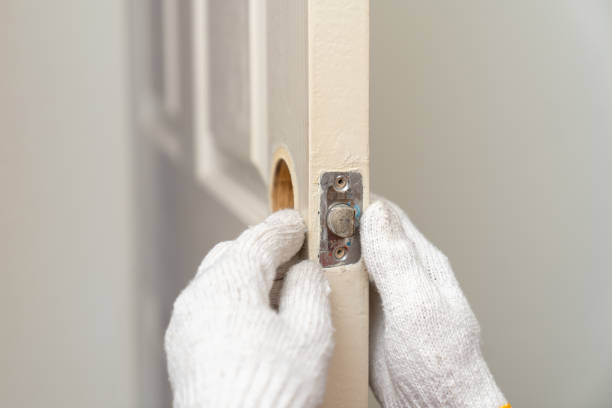 istock Locksmith man in uniform using a screwdriver installing or fixing door lock on wooden door in home. 1811453917