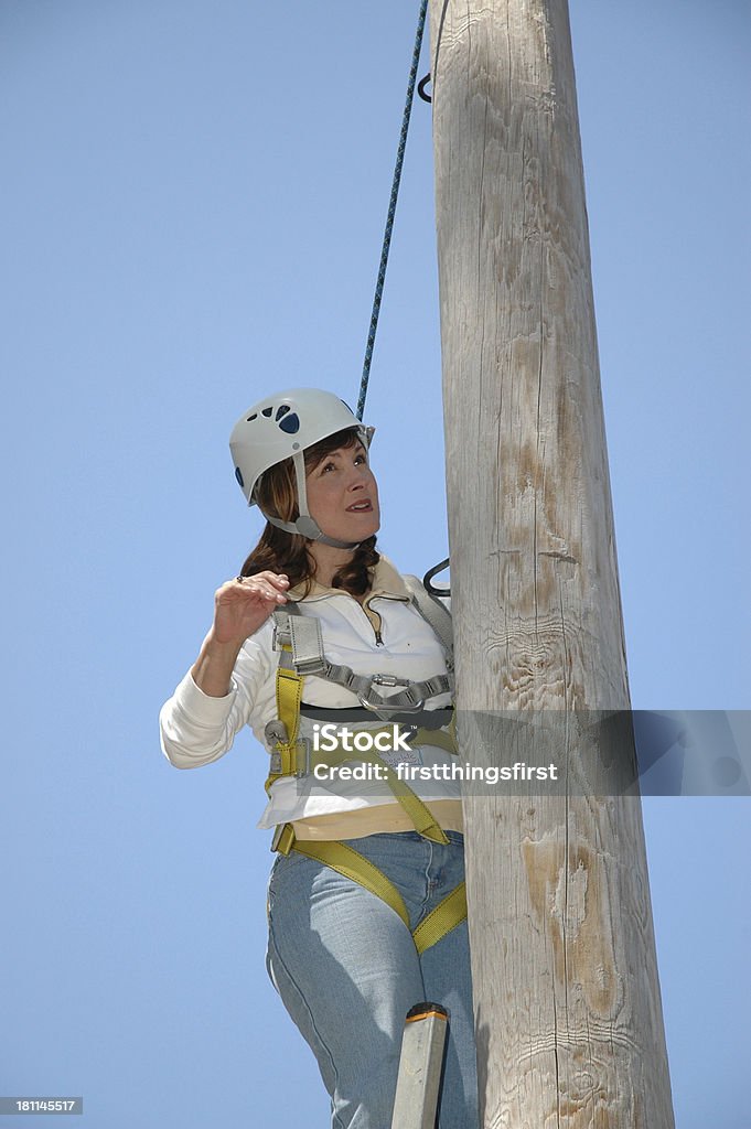 ropes course woman in a harness climbing a pole Adventure Stock Photo