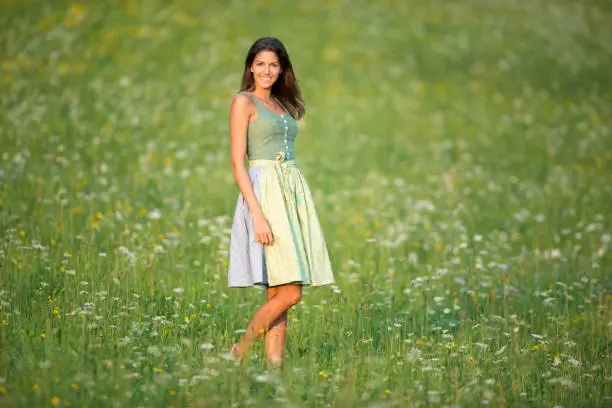 Beautiful woman in Dirndl Fashion standing in the Meadows on a beautiful summer day. Nikon D800e. Converted from RAW.