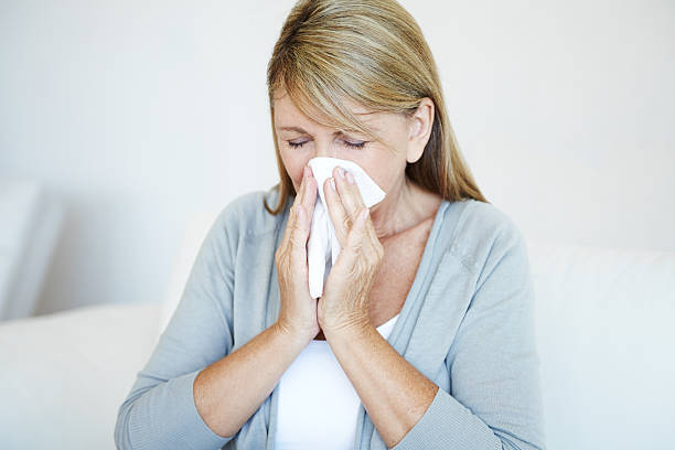 istock Blonde woman blows nose into tissue 181146303