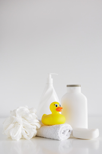 Bath concept - Sponge, douch gel, soap, towel and yellow duck on white table with copyspace