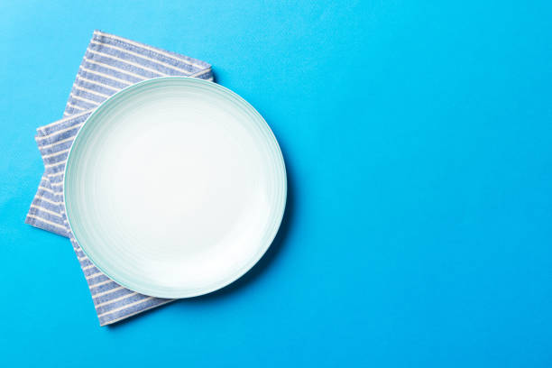istock Top view on colored background empty round blue plate on tablecloth for food. Empty dish on napkin with space for your design 1811465317