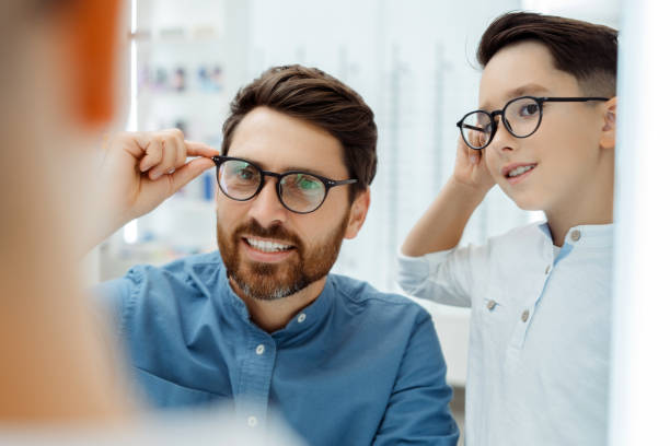 Smiling man and boy posing in optical store with glasses