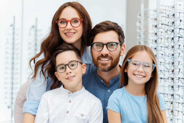 Happy family choosing eyeglasses frames in optical shop Smiling parents and their children in new glasses posing in optics. Health care, family concept group of people wearing eyeglasses stock pictures, royalty-free photos & images