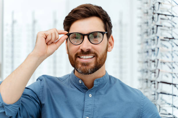 istock Smiling young man trying on spectacles in optical shop 1811471939