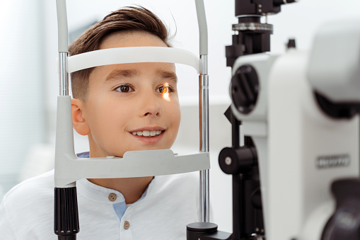 Little boy doing examination of the eyes while looking through autorefractor. Health care concept