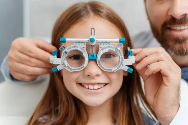 Photo of Happy girl sitting in the doctor cabinet and have tested her visual acuity