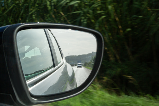 View of the road through the side mirror of the car