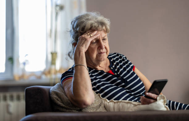 istock Elderly woman sitting on couch and using mobile phone at home 1811475998