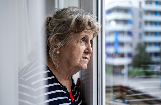 Portrait of thoughtful senior woman looking through window