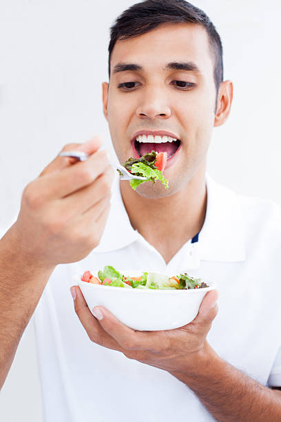 istock Young man eating a salad 181148027
